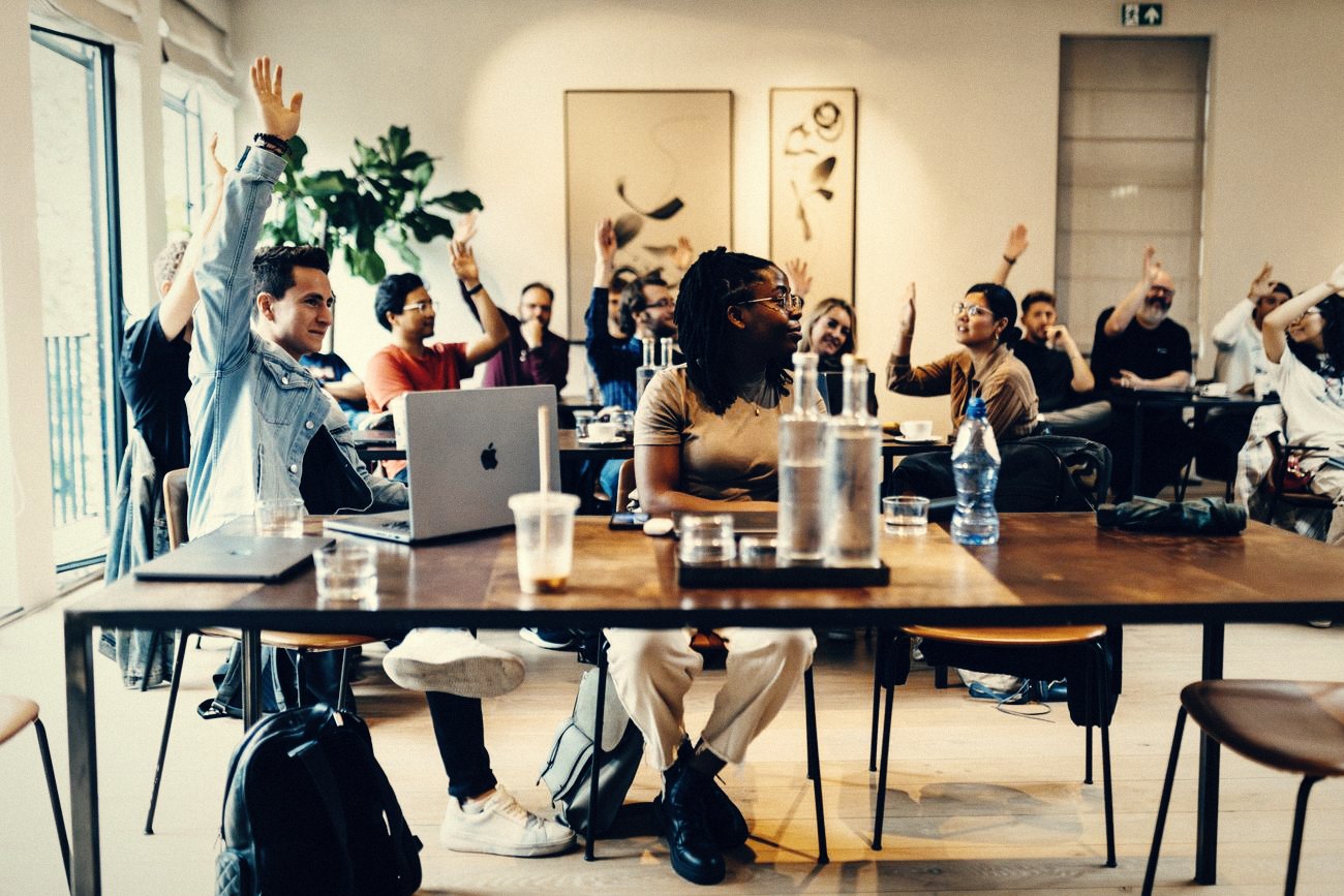 Een groep in een workshop, met opgestoken handen